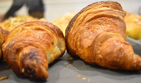 Golden-brown croissants on a dark surface with flaky, buttery layers visible