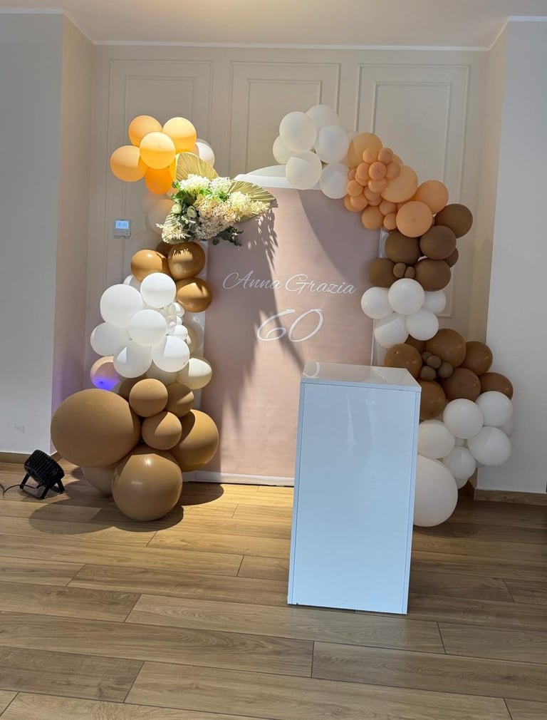 Elegant 50th birthday celebration setup with gold, white, and brown balloons arranged around a decorated mirror and white display stand