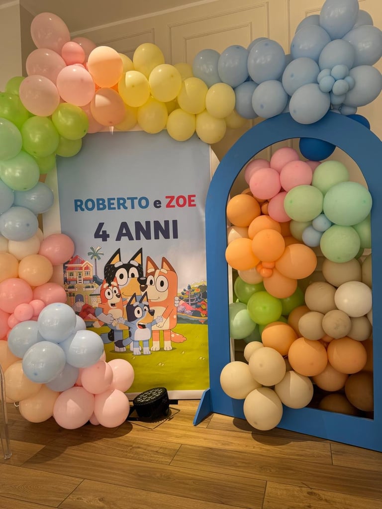 Colorful balloon decoration with Roberto e Zoe 4 Anni banner and blue balloon arch filled with balls